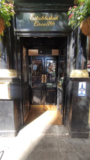 First set of black wood and glass doors. Push golden pads in centre to open.