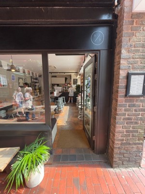 Glass door with black frame. Push from left to open.