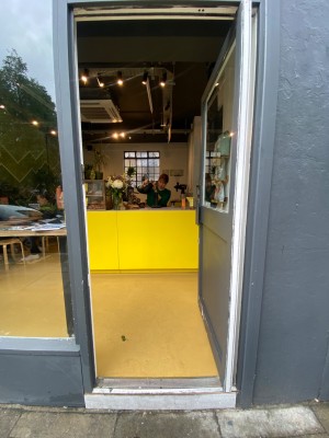 Grey door, with glass panel. Handle on left. Push to open.