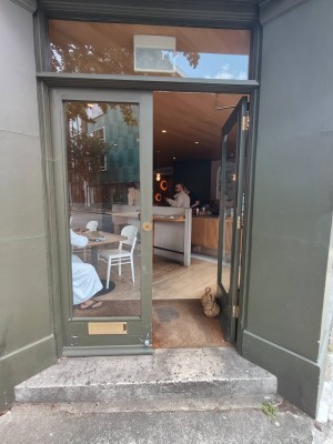 Facing entrance door. Green framed door. Push handle on left of right door to open.