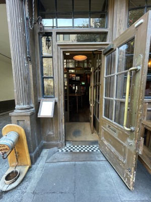 First set of doors ahead. Brass and glass door. Pull vertical golden handle on left to open. Dog bowl station left of door.