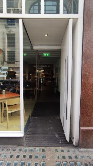 White door ahead. Pull via vertical metal handle to left to open.