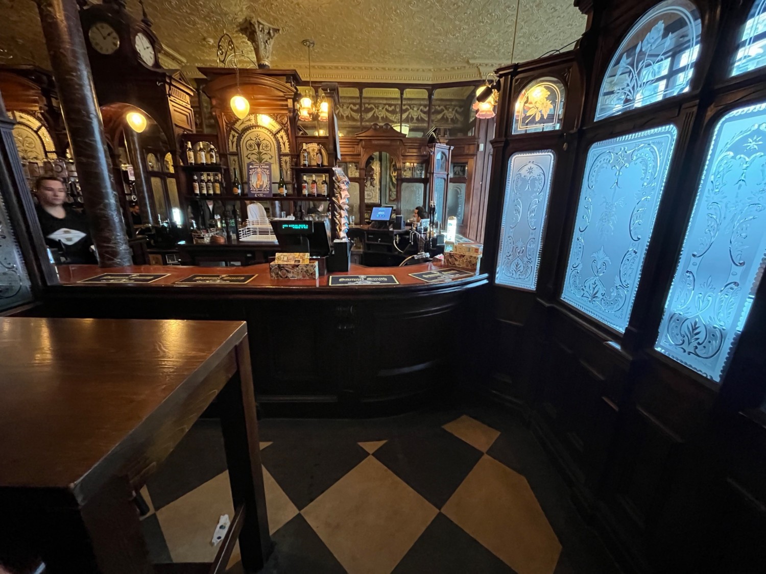 From archway facing straight. Bar along back wall. High table with stools on left.