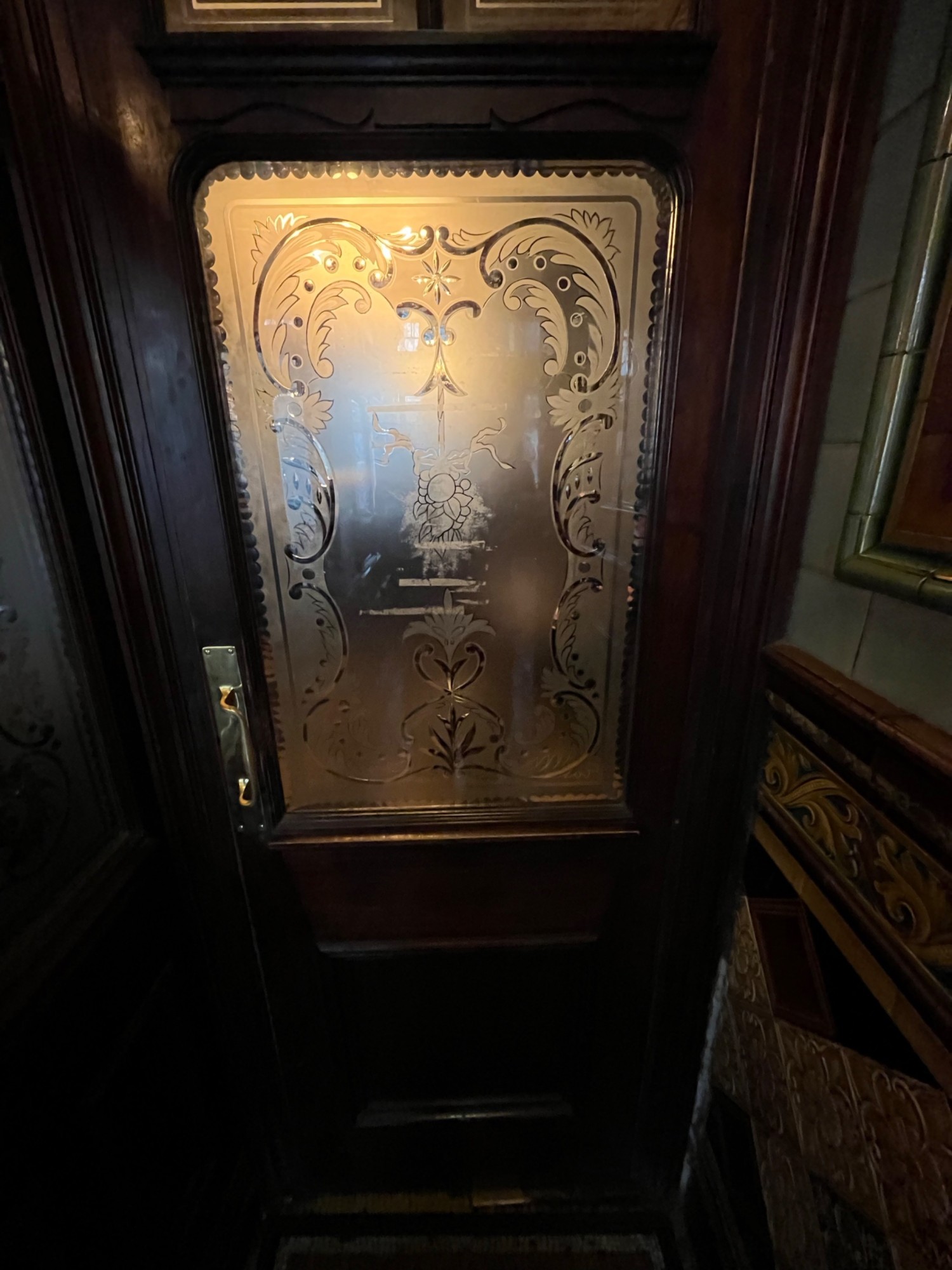 From end of path facing straight. Wood door with glass panel. Pull open via handle on left.