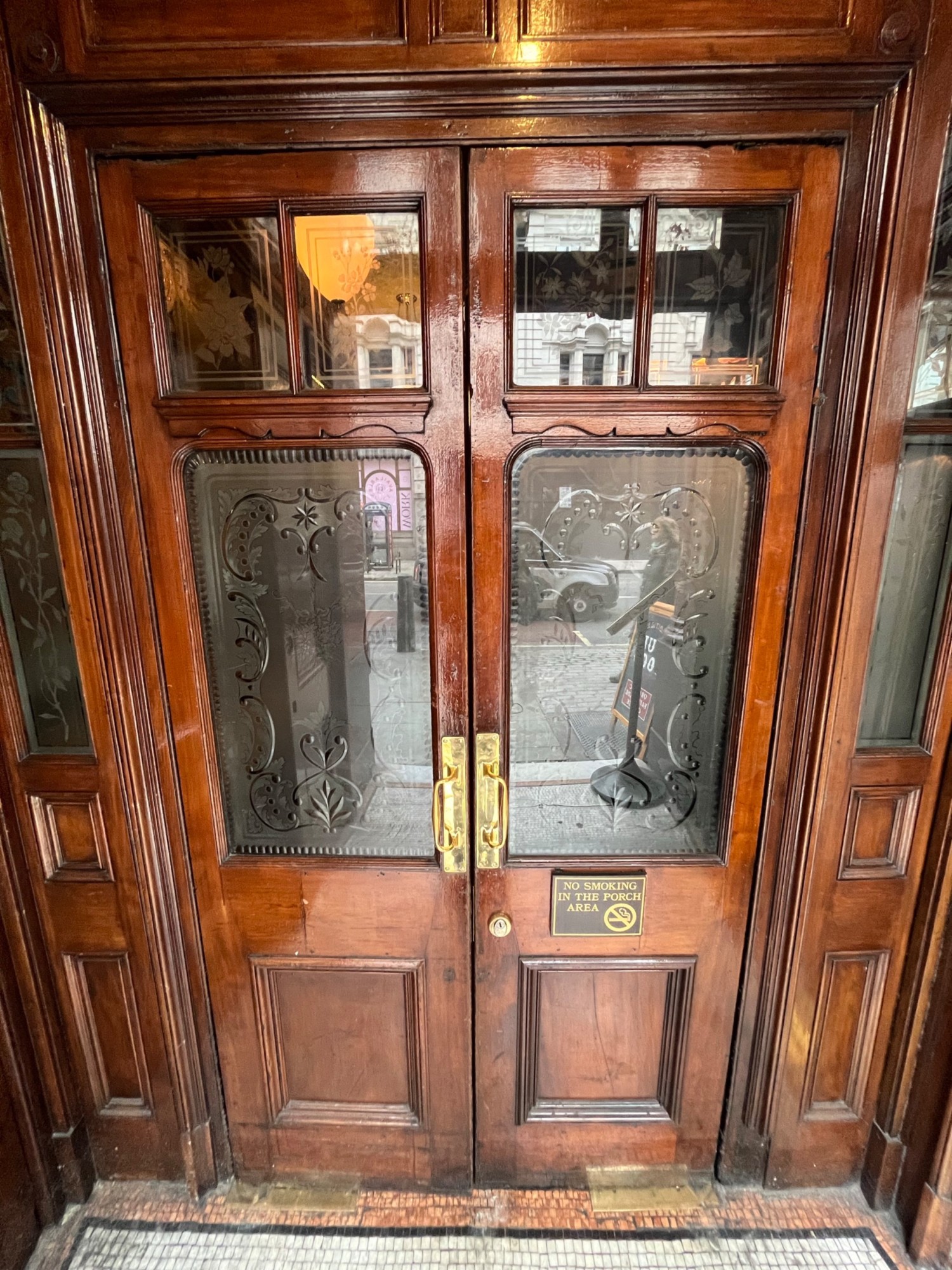 From left foyer facing straight. Wooden double doors with glass panels ahead. Pull open via handles in centre.