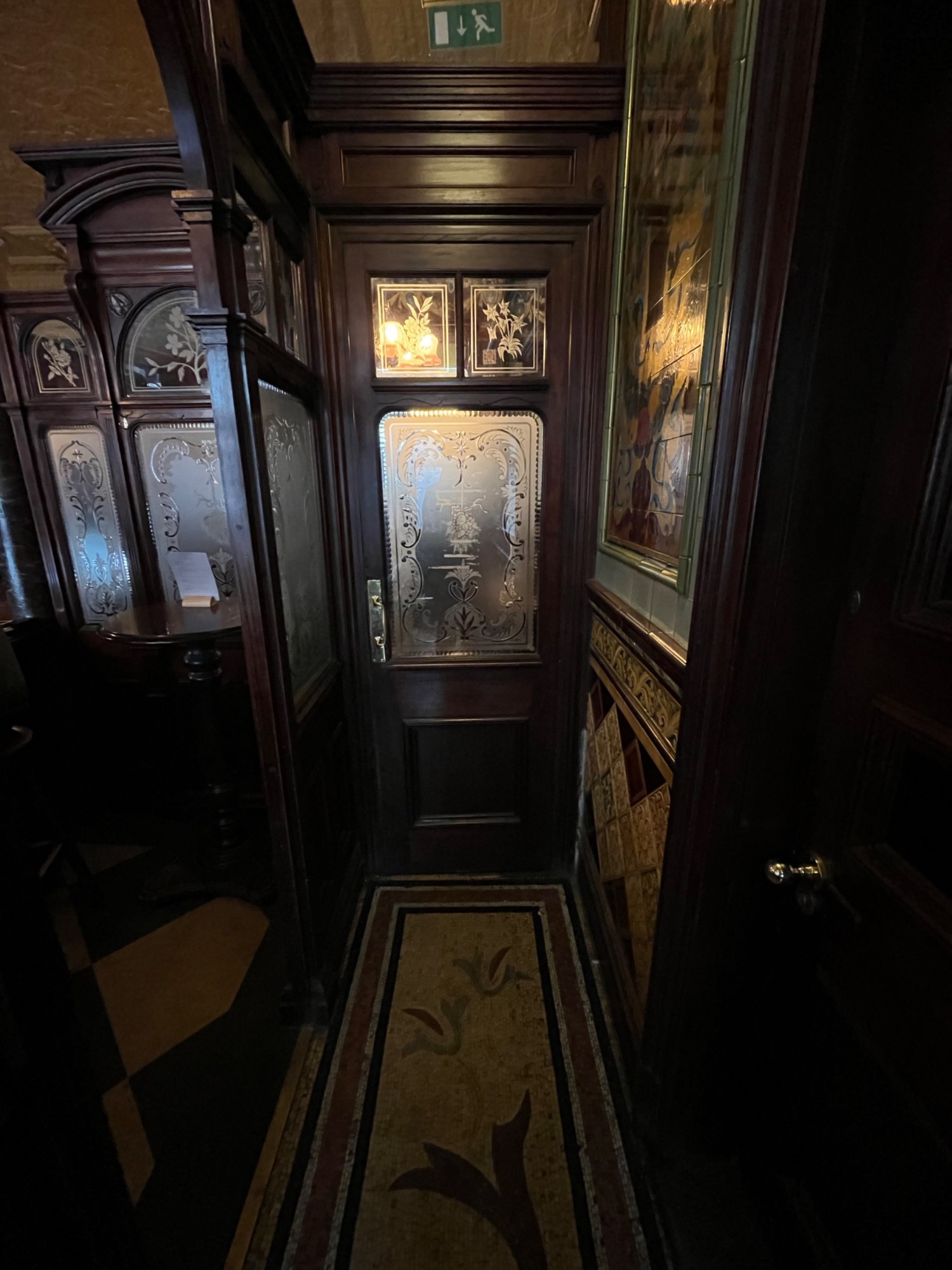 From further along path facing straight. Path continues ahead. Archway on left leads to second small room.