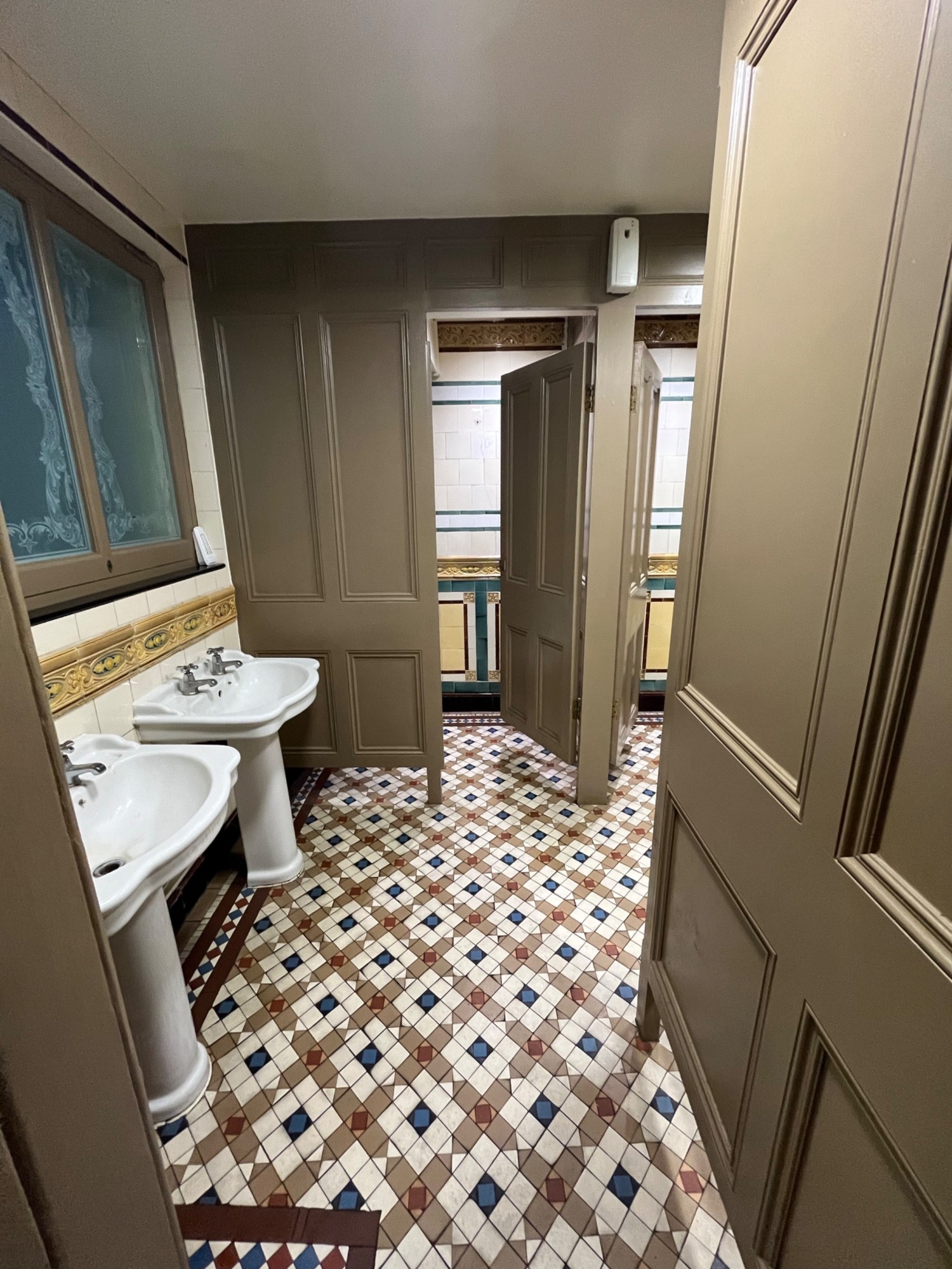 From door facing left. Sinks on left wall. Path ahead leads to cubicle.
