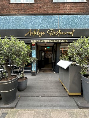 From pavement looking straight at opening ahead. Menu and planters to right and planter to left.