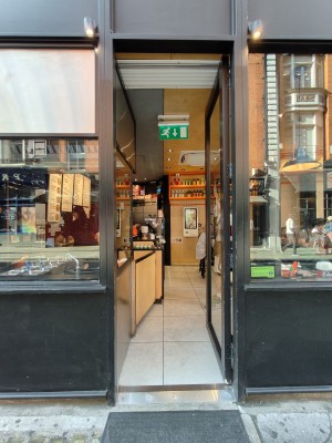 Facing single black framed glass door. Push black metal leaf on left to open.