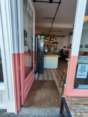 Facing white & pink framed entrance door. Push silver metal handle on right of door to open.
