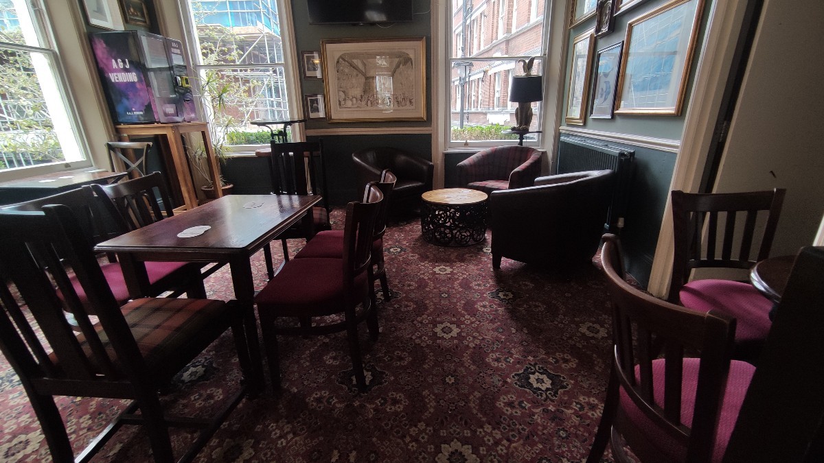 From top of staircase facing right. Path ahead. Tables and chairs on either side of it. Armchairs at the back.