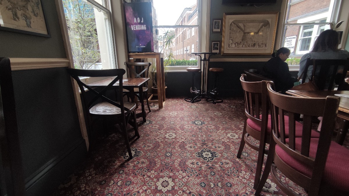 From end of counter facing right. Path ahead. Tables and chairs on either side.