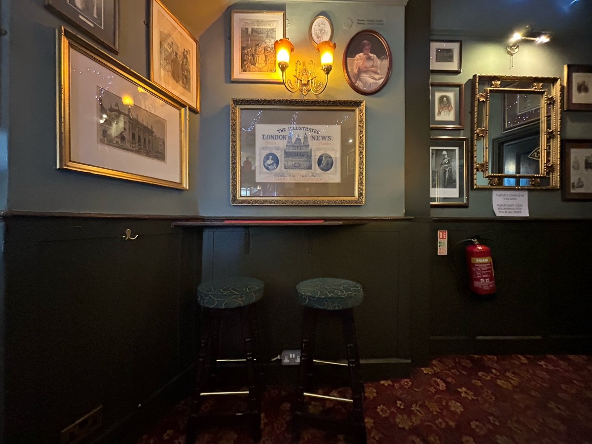 From end of bar facing left. High table and stools along back wall.