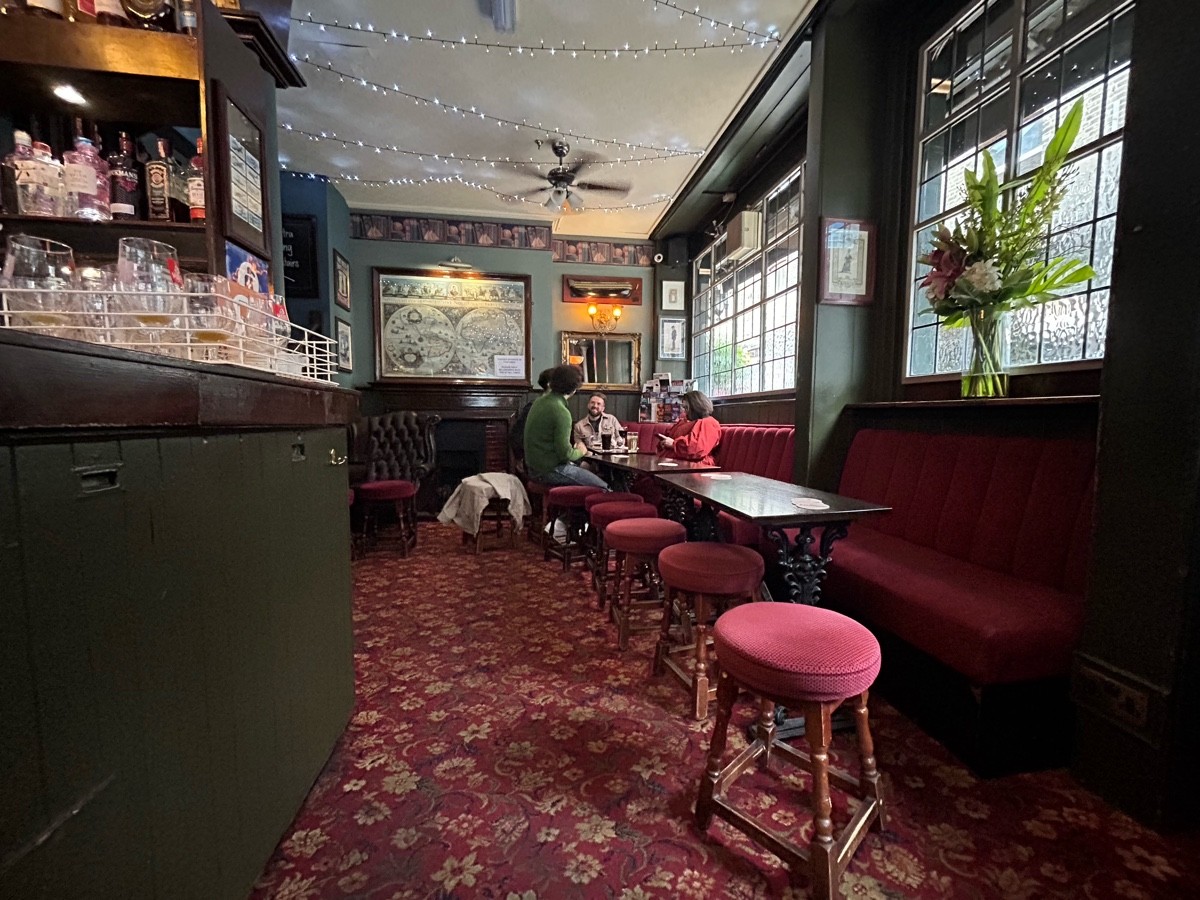 From start of half booths facing straight. Bar left. Half booths right. Path middle to armchair and stools back left.