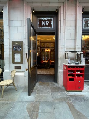 Path ahead. Red storage desk at back right. Metal-framed glass door at end of path. Pull brass handle on right to open.