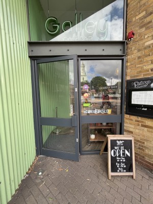 Glass door with grey frame ahead. Pull door to ope via handle on right.