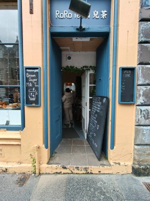 Facing entrance. Blue door ahead. Push in centre of doors to open. Pathway in centre obstructed by menu banner against the right door.