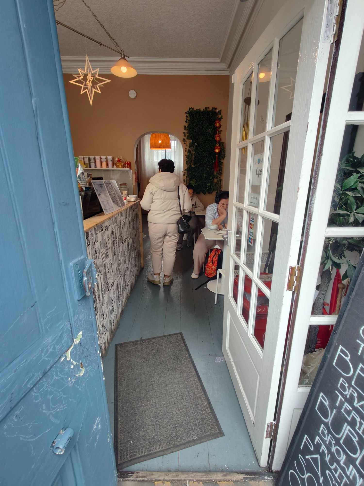 From door facing straight. White framed door ahead. Push silver metal handle on left of door to open.