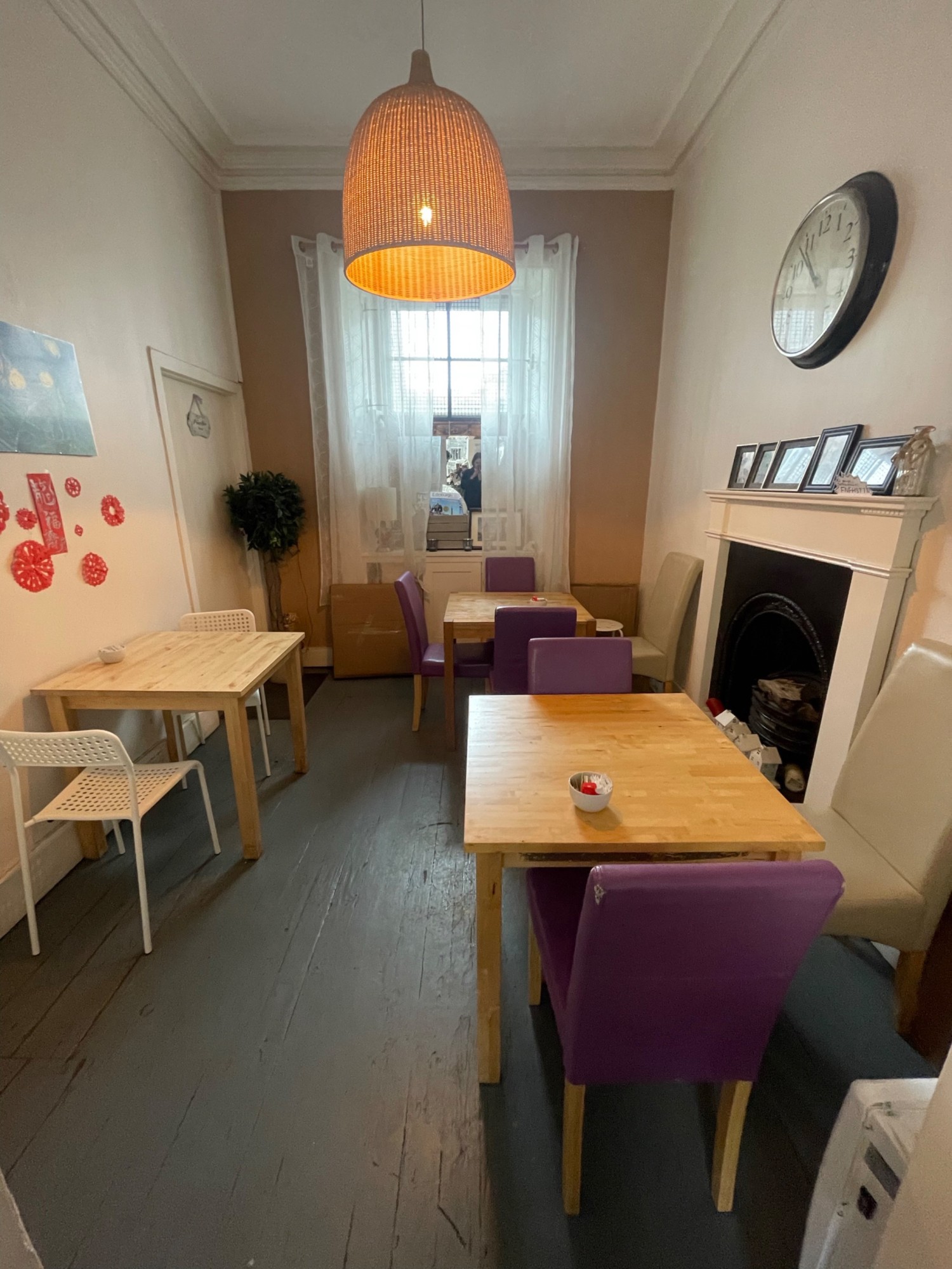 From archway looking straight. Two tables with chairs along right. Table with chairs on left. Path straight inbetween. Bathroom door in back left.