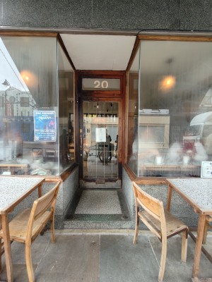 Facing archway to entrance door at back. Wooden framed glass door. Push brass handle on left to open.