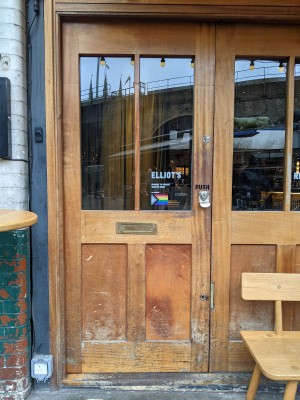 Glass and wood door with metal handle on right. Push to open. Doorbell left of door.
