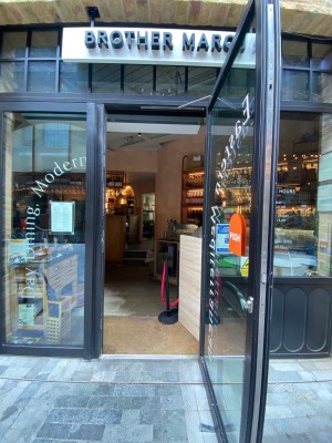 Glass door, with black doorframe. Vertical handle along left. Pull to open.