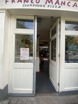 Glass double door, with white wooden doorframe. Push on left of right door to open.