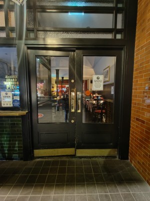 Facing black framed glass doors. Push from centre to open.