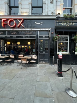 Restaurant barriers along right. Path to entrance ahead. First door at end of path.