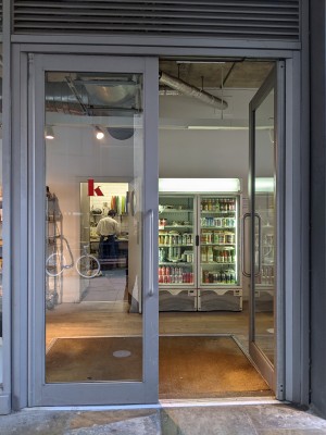 Glass doors with grey frame and metal handles in centre. Push to open.