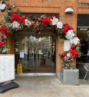 From pavement facing venue. Glass doors ahead, pull from metal handles in centre to open. Standing sign to left.