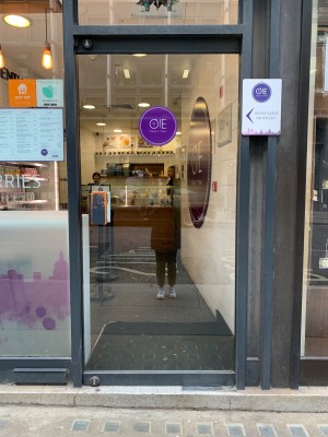 Glass door with black frame. Push from black handle on left to open.