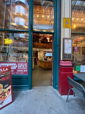 Facing venue entrance. Single glass door with red frame. Push brass handle in center to open.