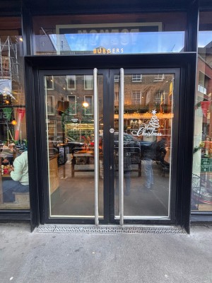 Double glass door with black frame ahead. Pull metal handle at left of right door to open.