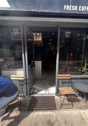 Facing grey entrance door. Push silver metal handle on right of door to open.