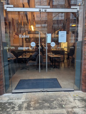 From back right of stairs looking ahead. Glass doors with handles in the middle. Push to open.