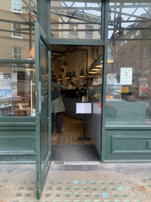 Glass door with green wooden frame ahead. Pull from handle on right to open.