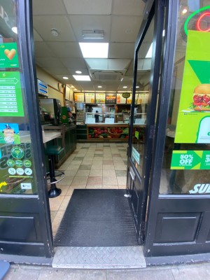 Glass door, with black doorframe. Handle on left. Push to open.