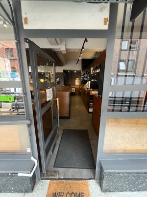 Grey framed glass door. Push open via handle on right.