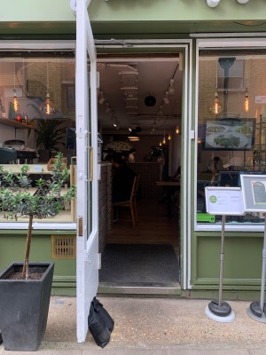 Glass door with green and white wooden frame ahead. Pull from handle on right to open.