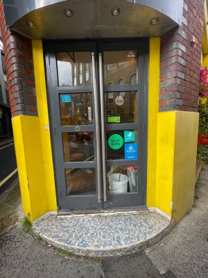 Double glass door with grey frame. Pull vertical metal handle on right of left door to open.