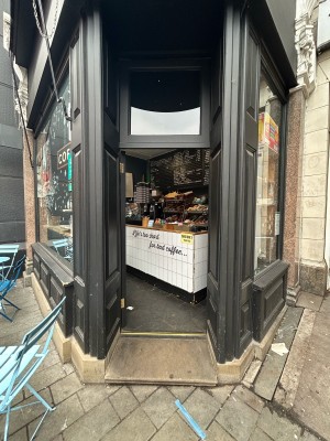 Single black wooden door with glass panel. Gold handle on right, push to open.