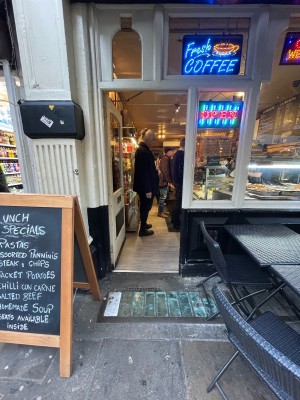 From pavement facing venue. Restaurant sign on left. White wooden door with glass panel. Twist doorknob on right to open.