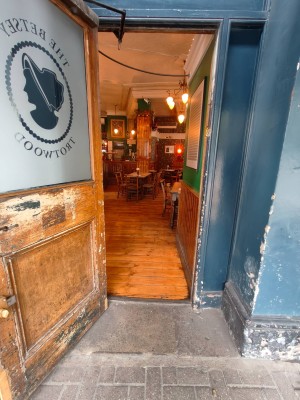 Facing entrance door. Blue framed door. Pull round metal handle on right of door to open.