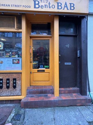 Glass door with yellow frame ahead. Push metal handle at left to open.