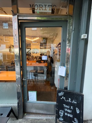 Grey framed glass door. Push open via handle on left.