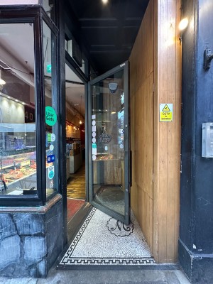 Opening straight ahead. Glass door with grey doorframe to left. Grey handle to left of door, pull to open.