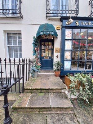 From pavement facing venue. Two steps up to landing before door.