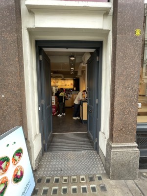 Grey double door with handle in centre, push to open. Signboard at left.