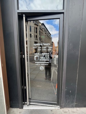 Black framed glass door. Push open via handle on left.